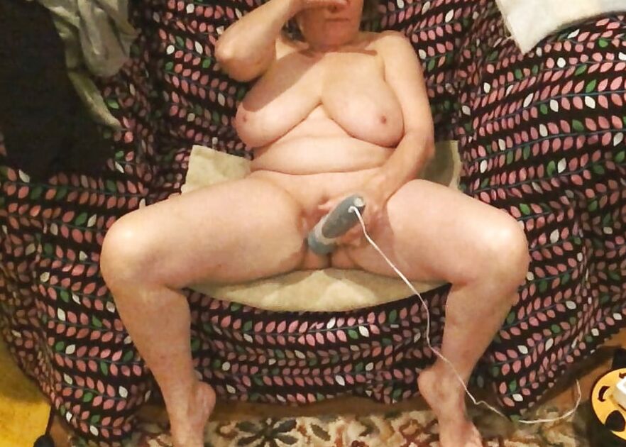 Mom plays with her vibrator in a big chair