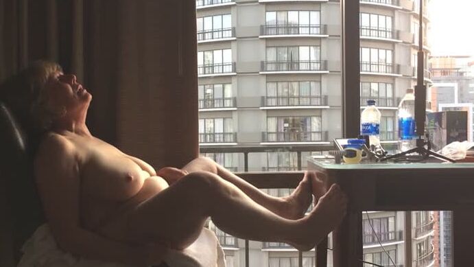 Mature masturbating GILF plays peek-a-boo with the city