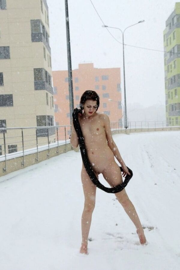 Short-haired brunette walks naked at winter streets