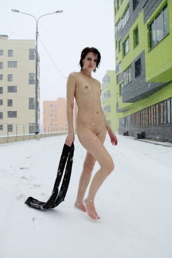 Short-haired brunette walks naked at winter streets