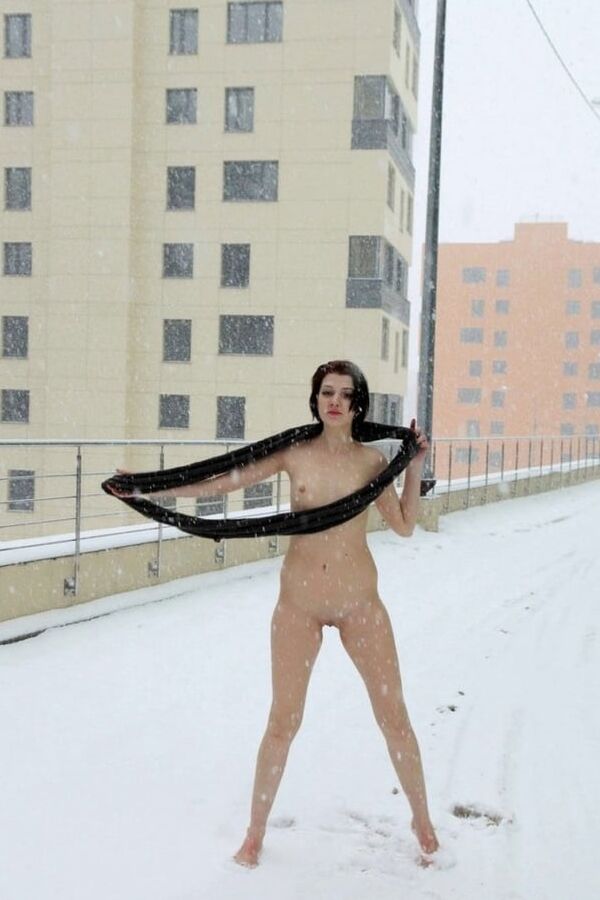 Short-haired brunette walks naked at winter streets