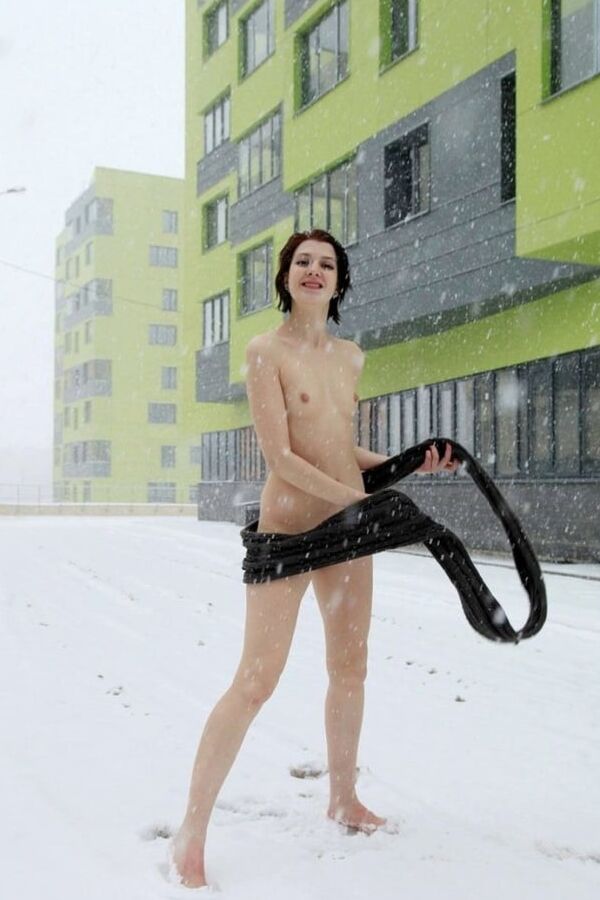 Short-haired brunette walks naked at winter streets