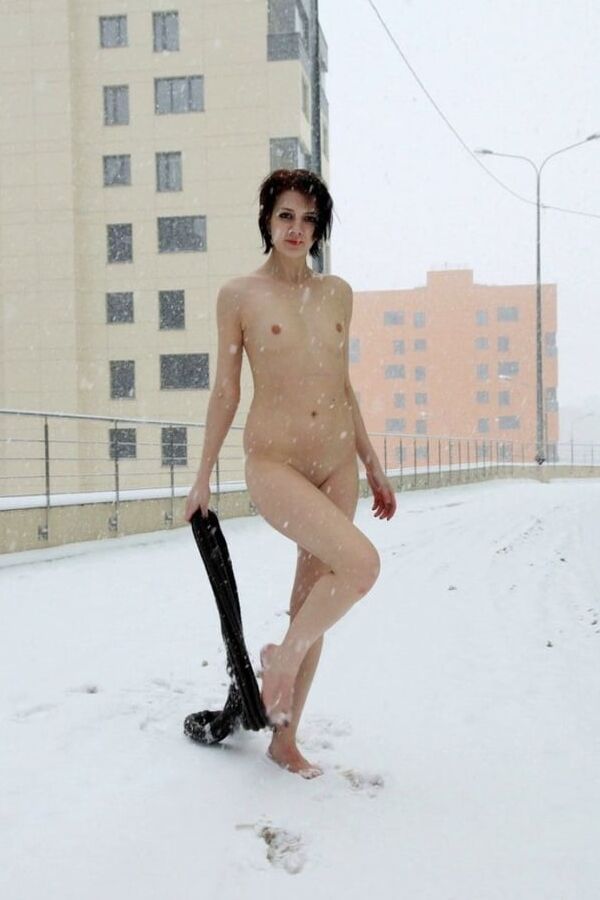 Short-haired brunette walks naked at winter streets