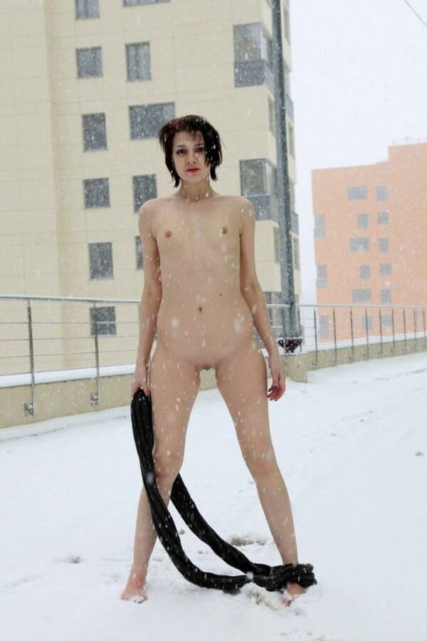 Short-haired brunette walks naked at winter streets