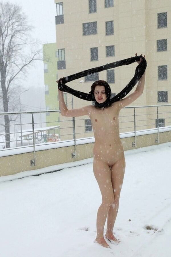 Short-haired brunette walks naked at winter streets
