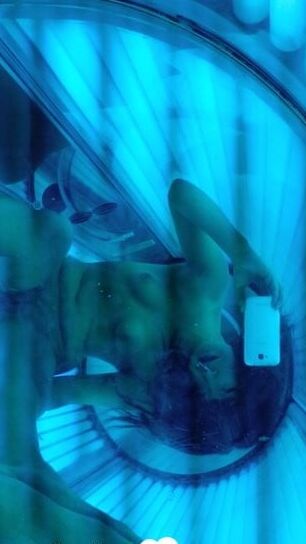 Asian sweetie taking selfies while tanning her body
