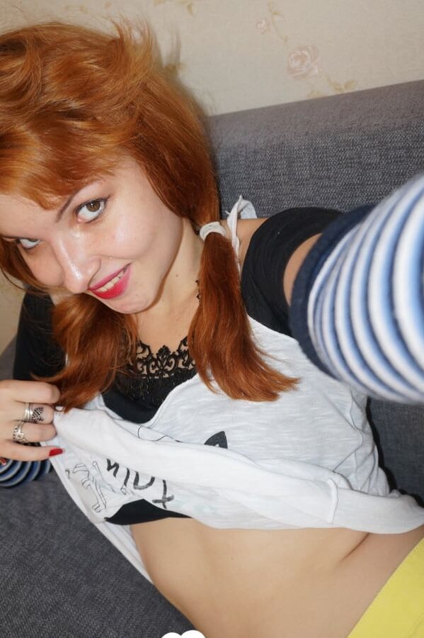 Redhead lifts her shirt to show her tits