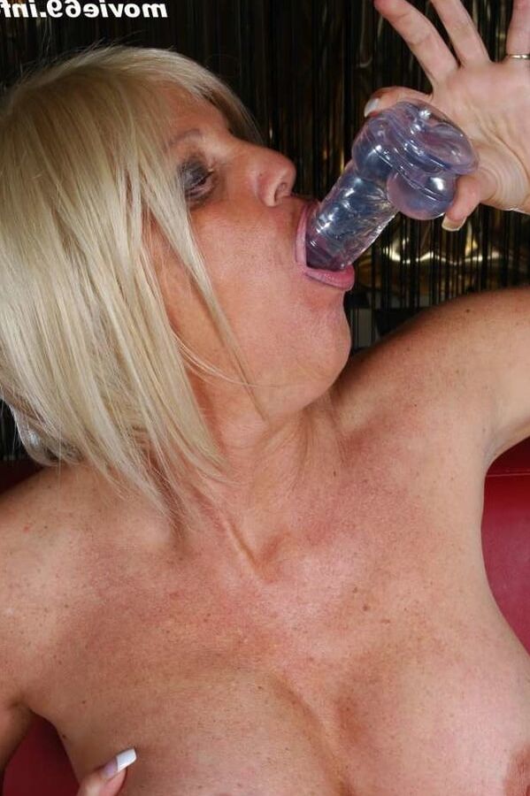 Jill is lying on a sofa with a dildo in her mouth and pussy
