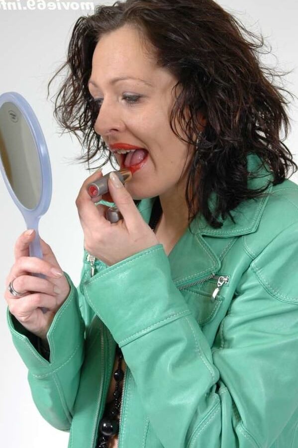MILF Lea is making up her lips in a green leather jacket