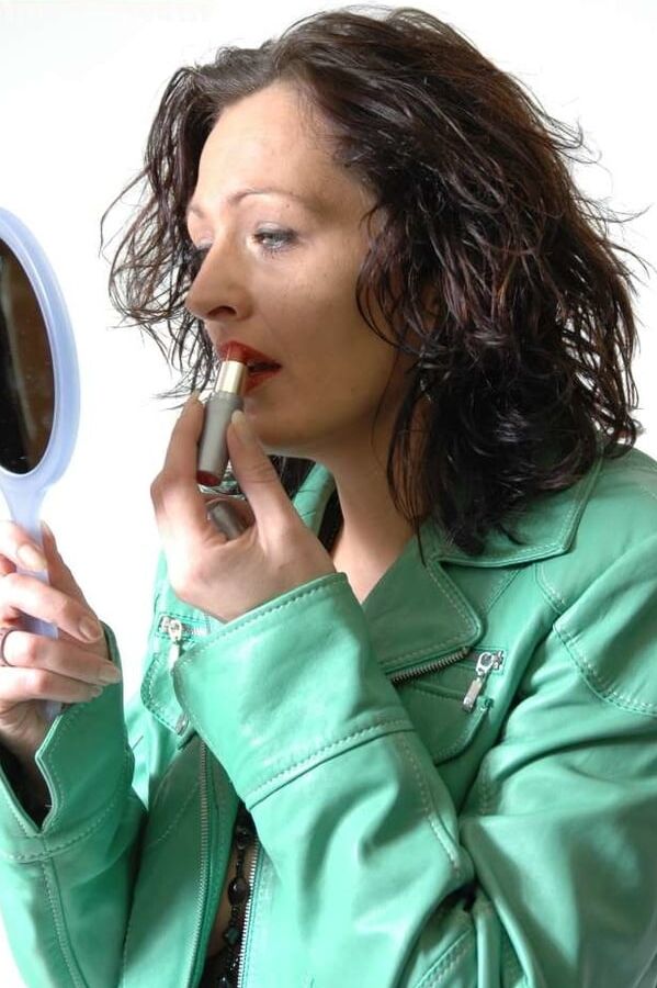 MILF Lea is making up her lips in a green leather jacket