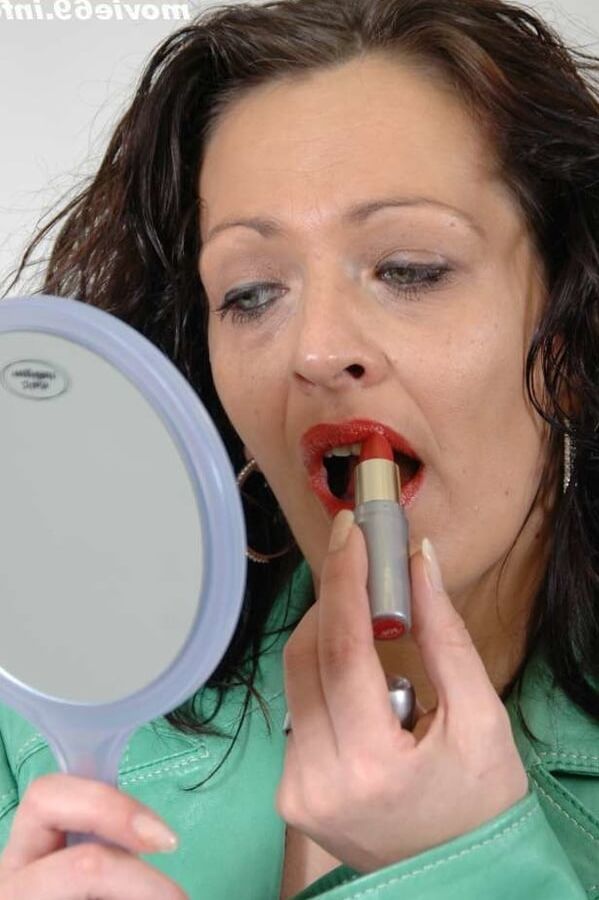MILF Lea is making up her lips in a green leather jacket