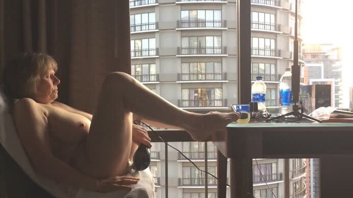 Mature masturbating GILF plays peek-a-boo with the city