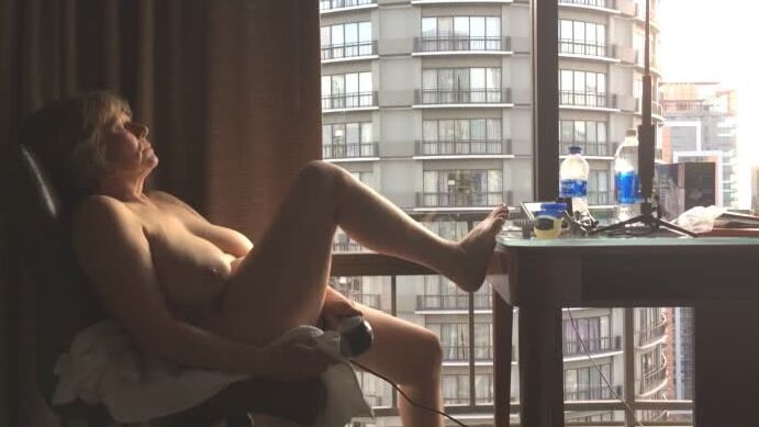 Mature masturbating GILF plays peek-a-boo with the city