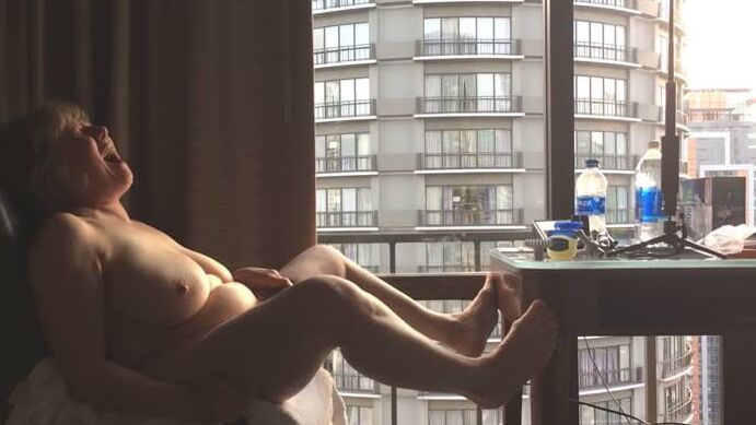 Mature masturbating GILF plays peek-a-boo with the city