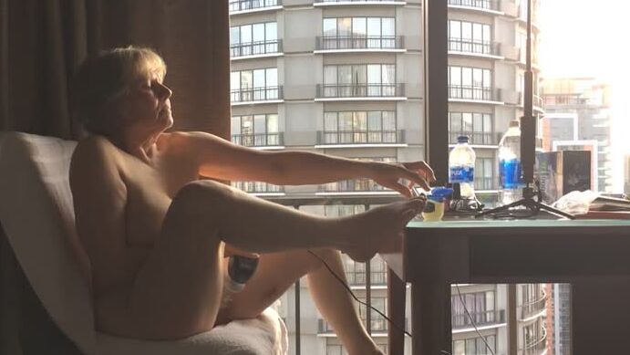 Mature masturbating GILF plays peek-a-boo with the city