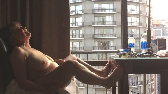 Mature masturbating GILF plays peek-a-boo with the city
