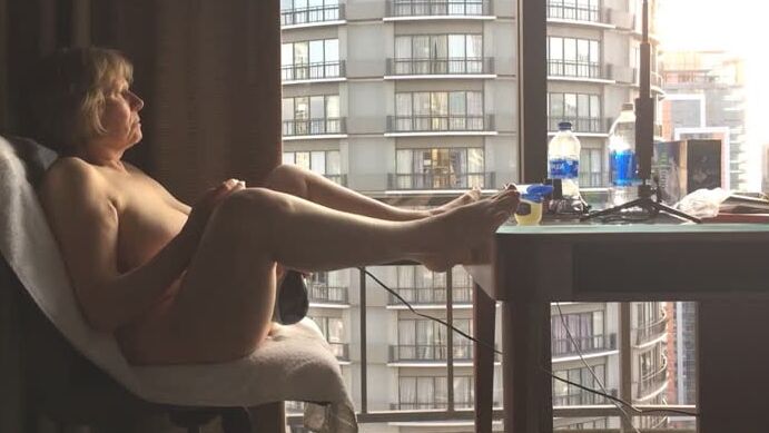 Mature masturbating GILF plays peek-a-boo with the city