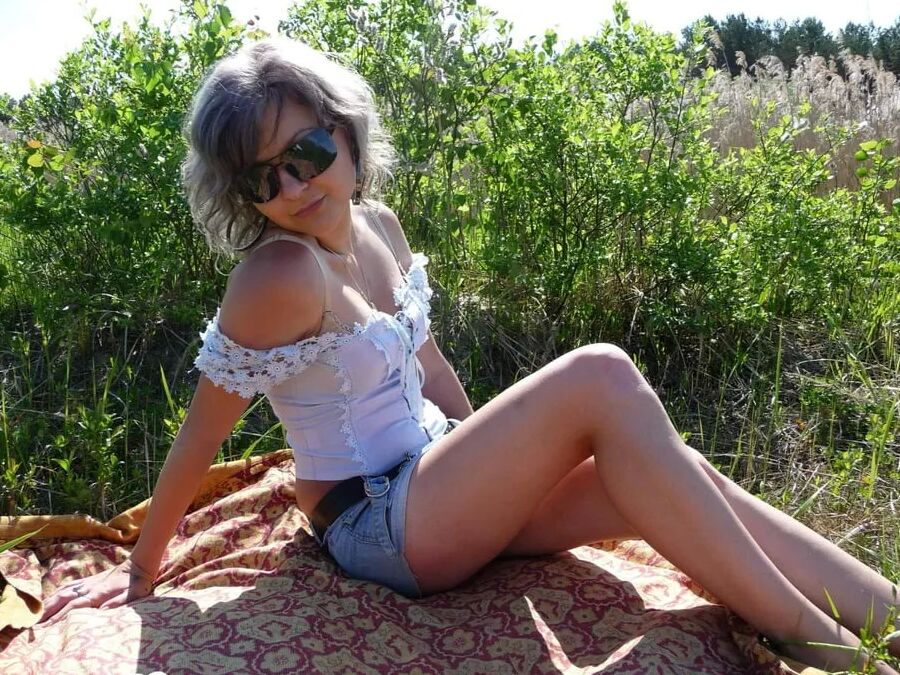 Gray-haired beauty posing naked outdoors on a blanket