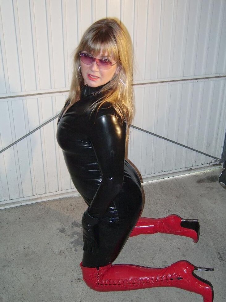 Fetish wife wearing tight latex catsuit and red heeld boots