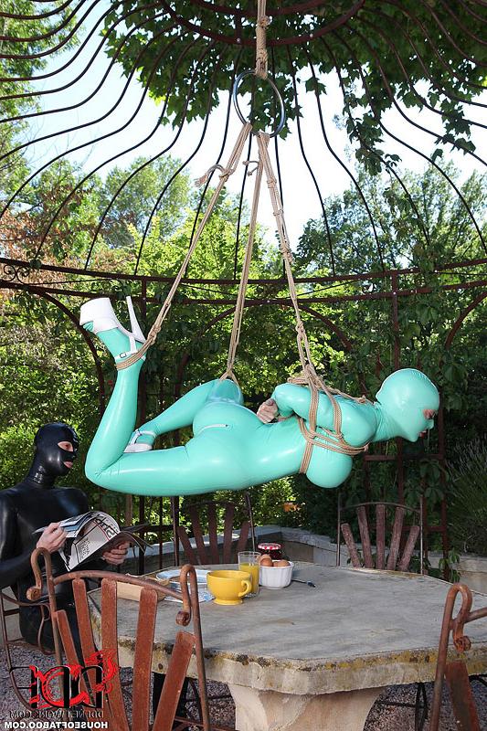 16P BDSM fetish model Latex Lucy suspended by ropes in latex outfit outdoors