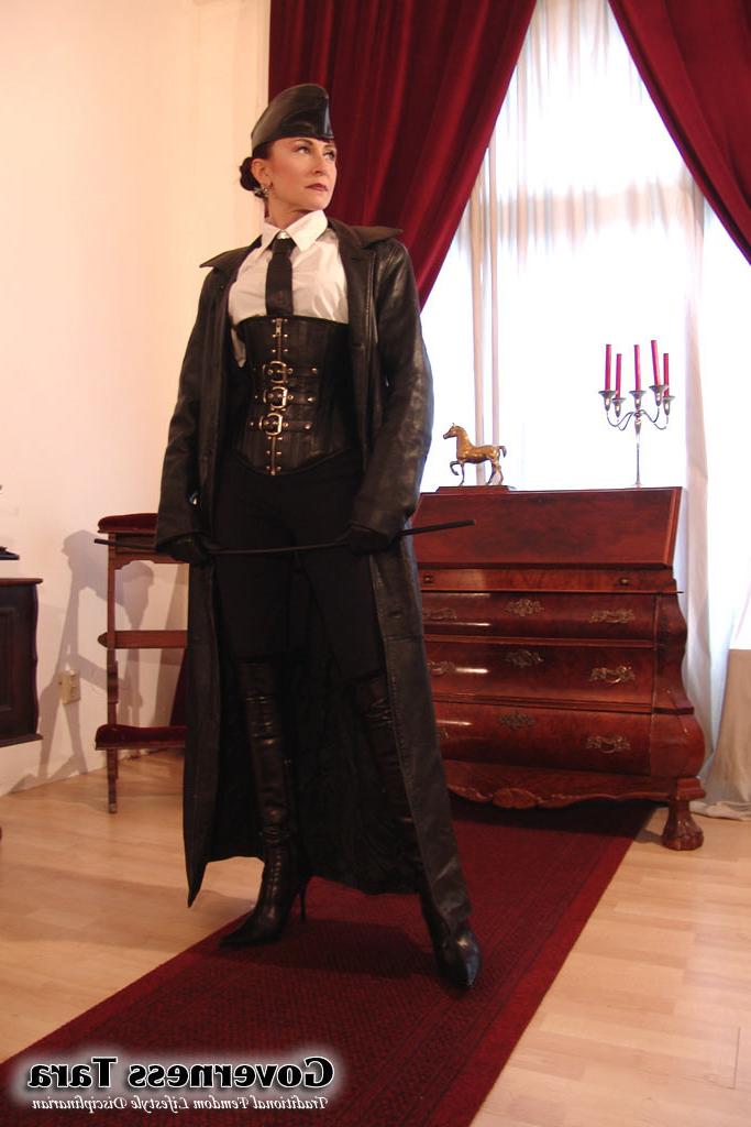 20P Twisted corsetted domina poses in spike heel leather boots