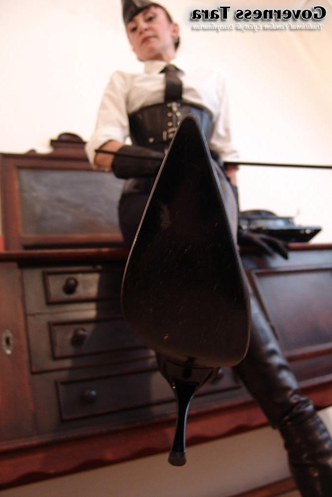 20P Twisted corsetted domina poses in spike heel leather boots