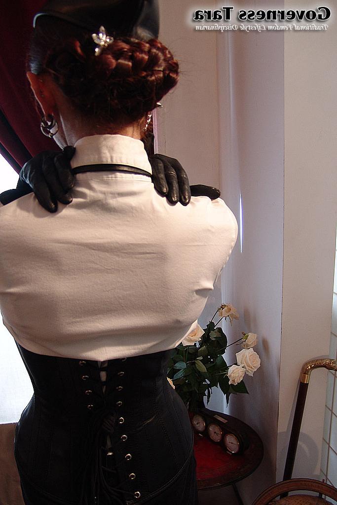 20P Twisted corsetted domina poses in spike heel leather boots