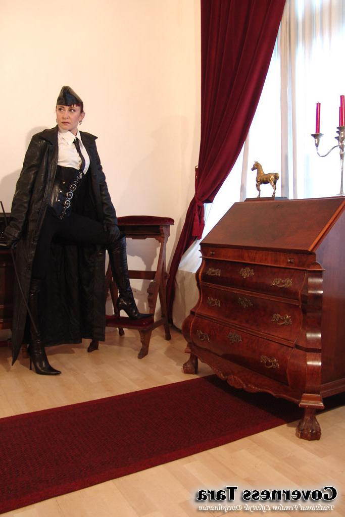 20P Twisted corsetted domina poses in spike heel leather boots