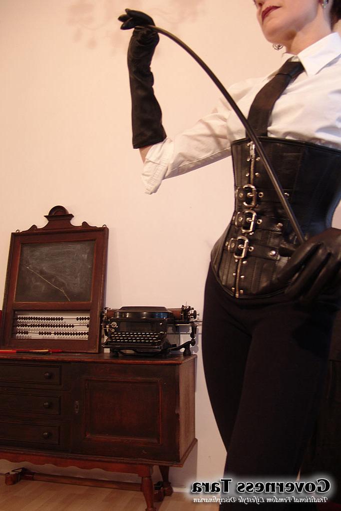 20P Twisted corsetted domina poses in spike heel leather boots