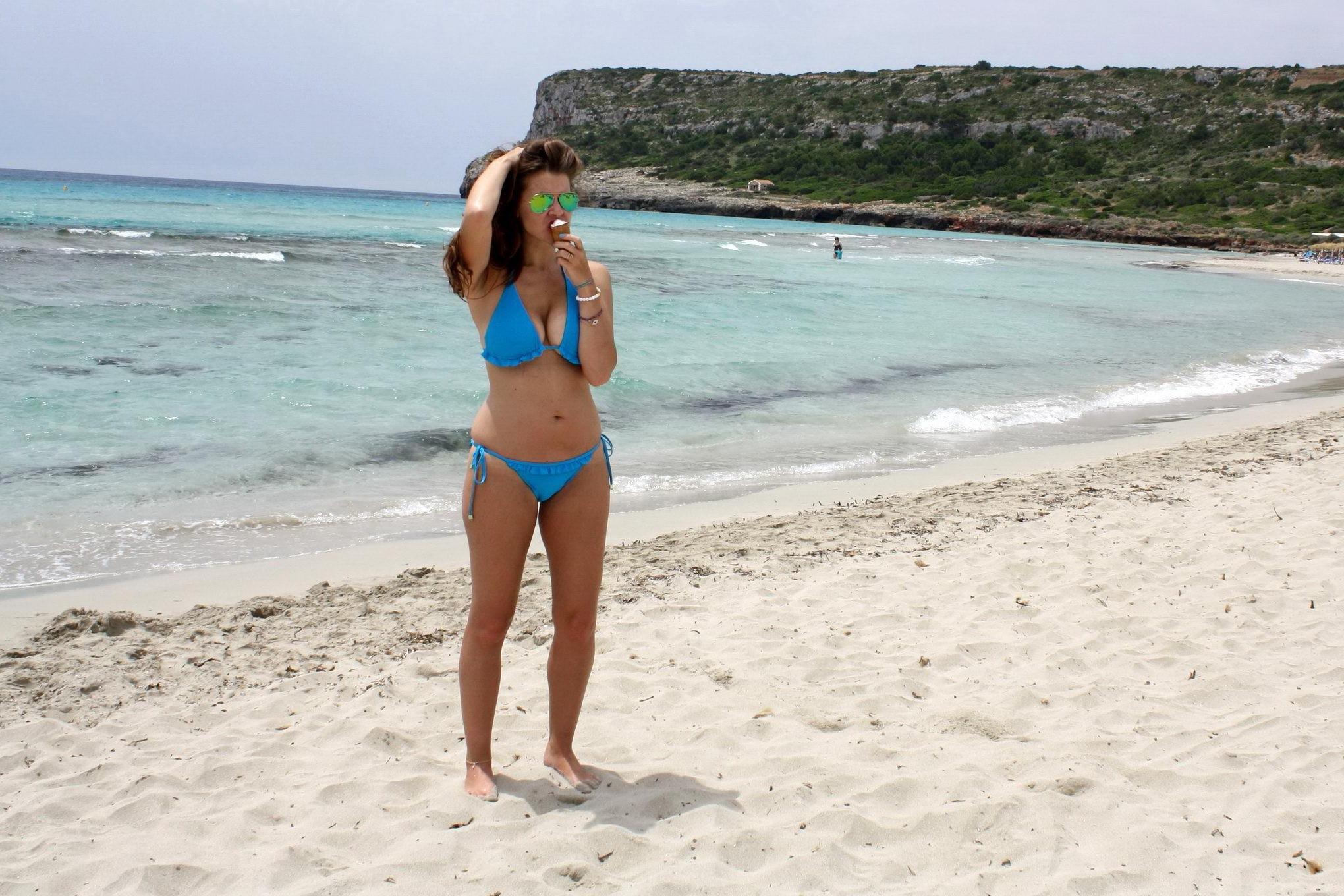 16P Busty Imogen Thomas in blue bikini eating an ice cream on a Spanish beach