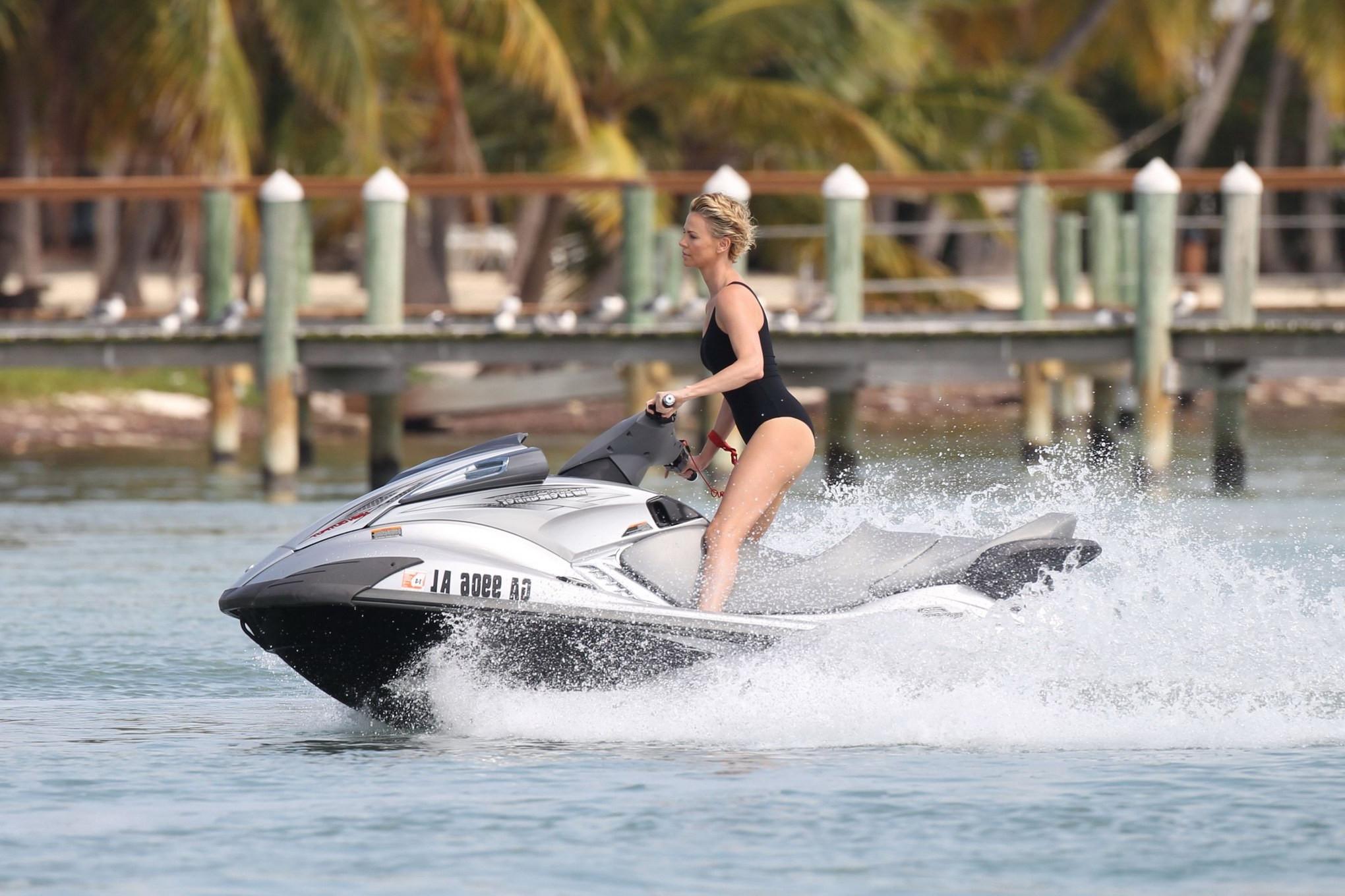 16P Charlize Theron jet skiing in black monokini during the photoshoot in Miami Beac