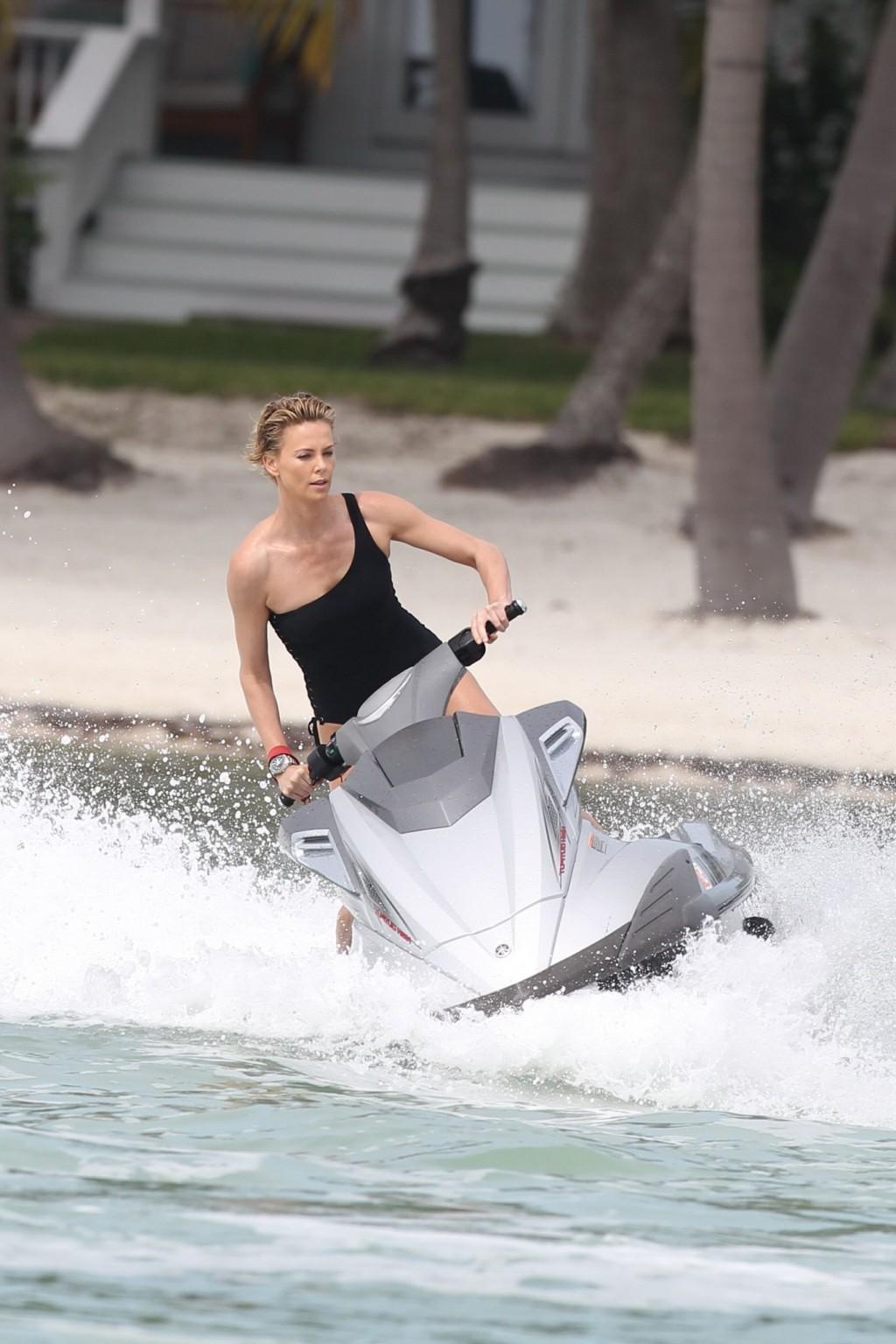 16P Charlize Theron jet skiing in black monokini during the photoshoot in Miami Beac