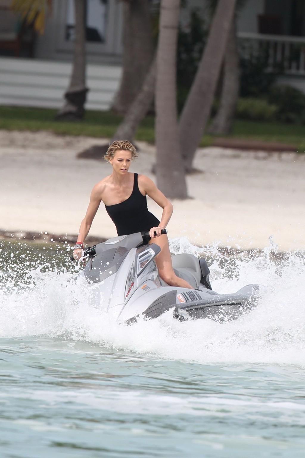 16P Charlize Theron jet skiing in black monokini during the photoshoot in Miami Beac