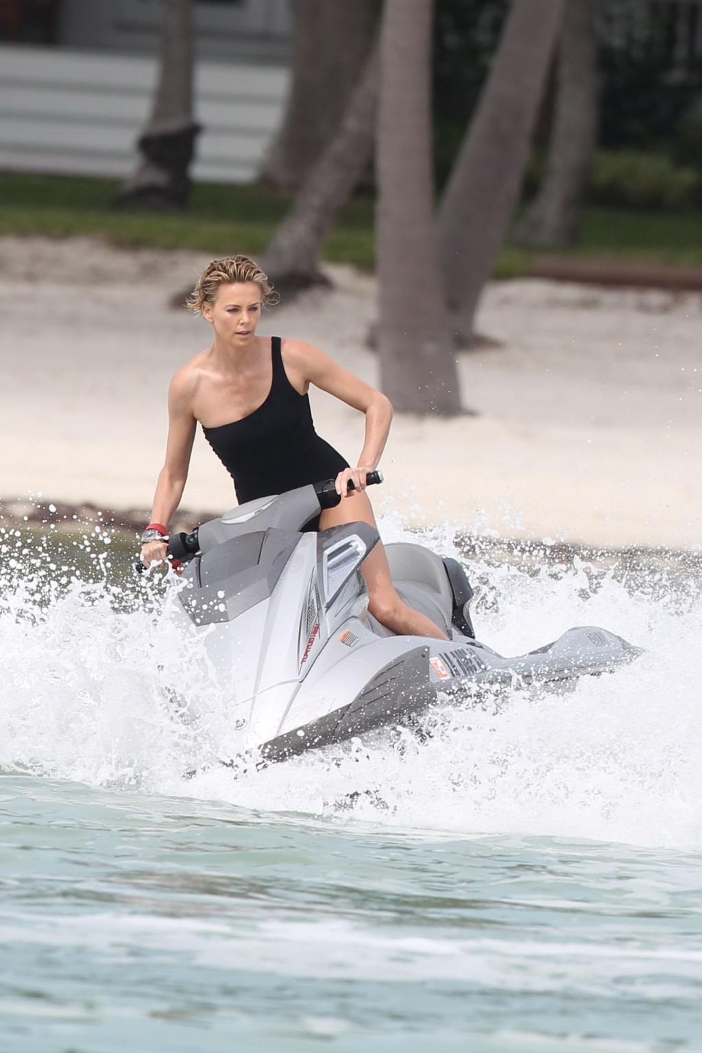 16P Charlize Theron jet skiing in black monokini during the photoshoot in Miami Beac