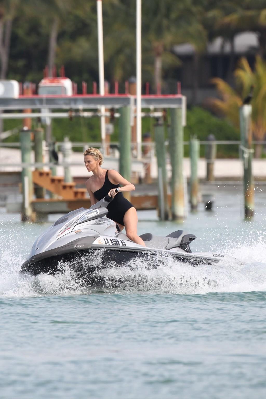 16P Charlize Theron jet skiing in black monokini during the photoshoot in Miami Beac