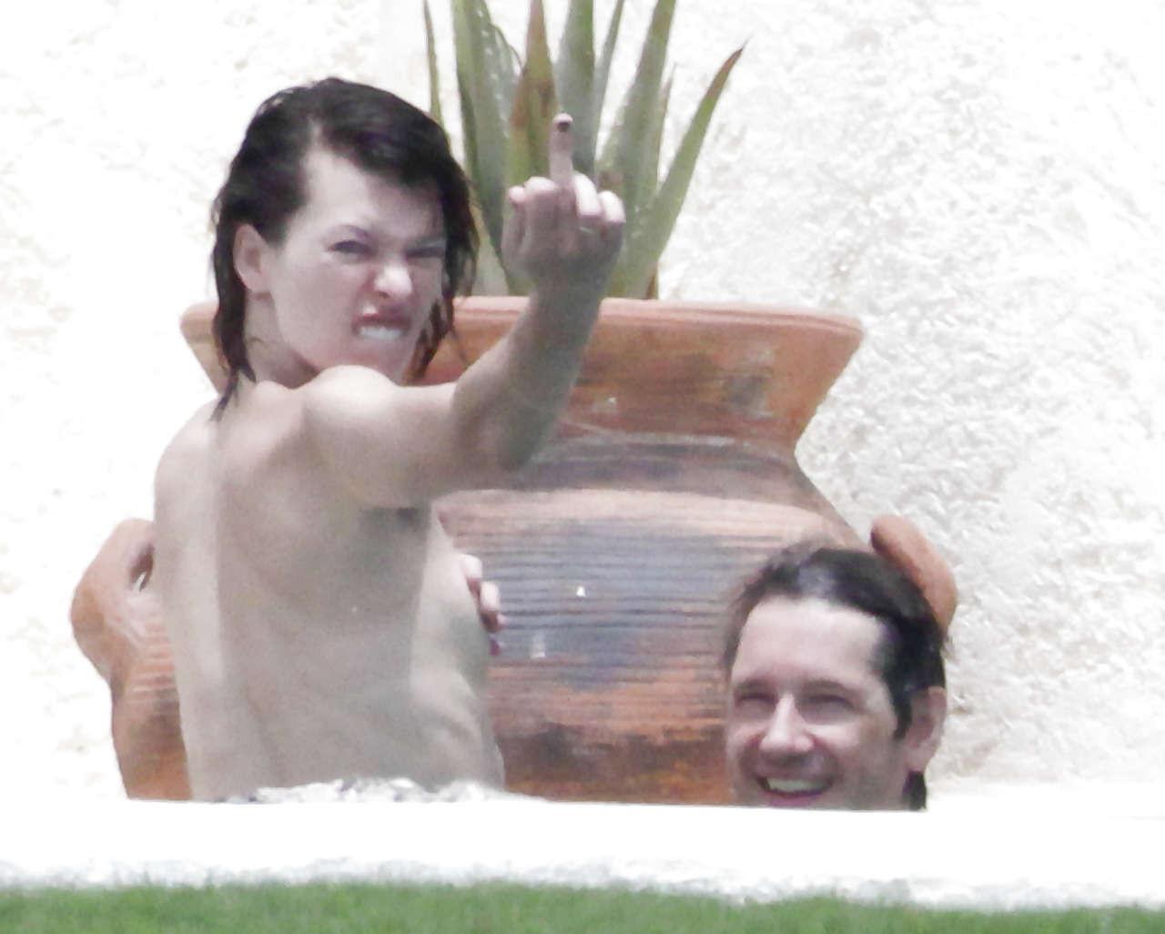 16P Milla Jovovich caught topless in pool by paparazzi and giving them middle finger