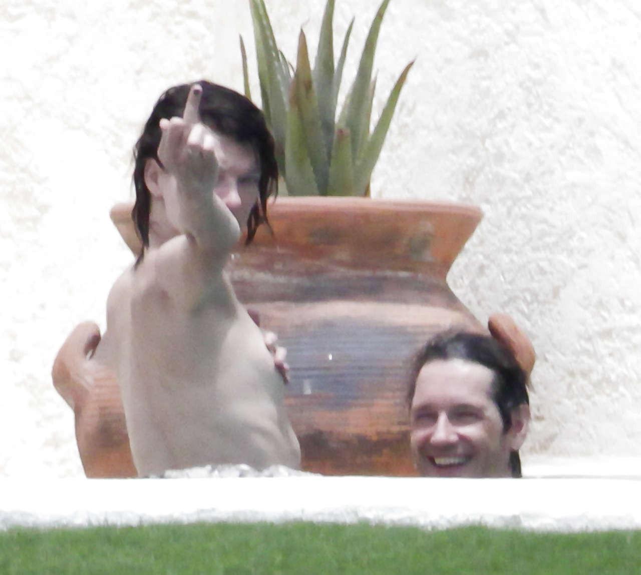 16P Milla Jovovich caught topless in pool by paparazzi and giving them middle finger
