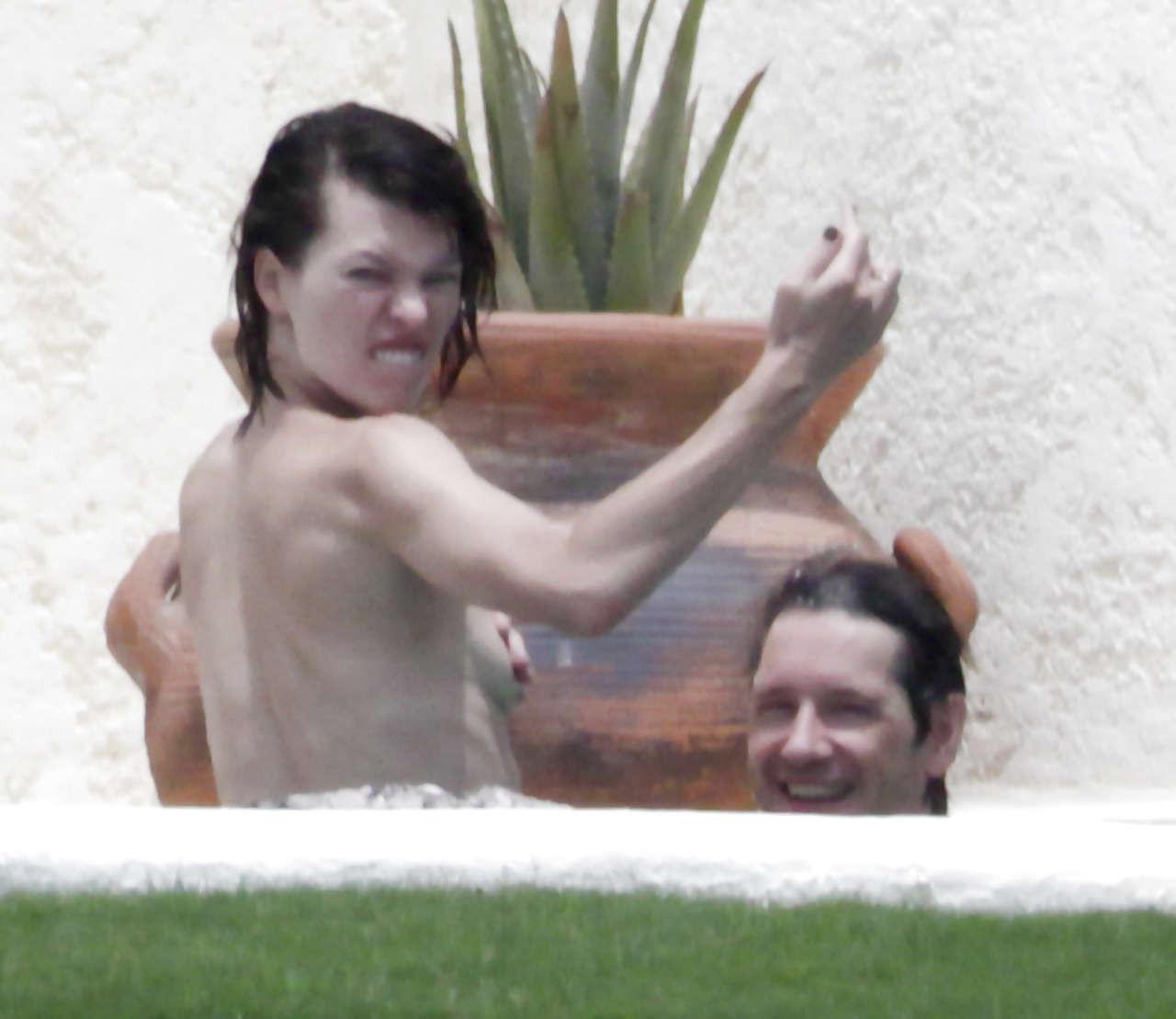 16P Milla Jovovich caught topless in pool by paparazzi and giving them middle finger
