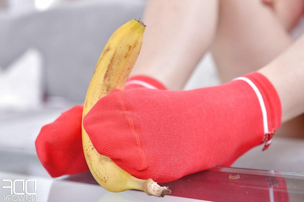 16P Leggy babe Ariana Brown squashing banana with barefeet after socks removal