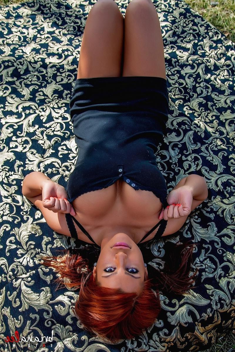 15P Busty girl Briana Lee lifts her black dress to toy her wet pussy outside