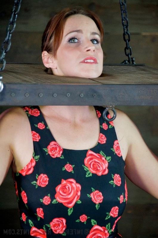 16P Bella Rossi in dress and stockings is bound in wooden stock