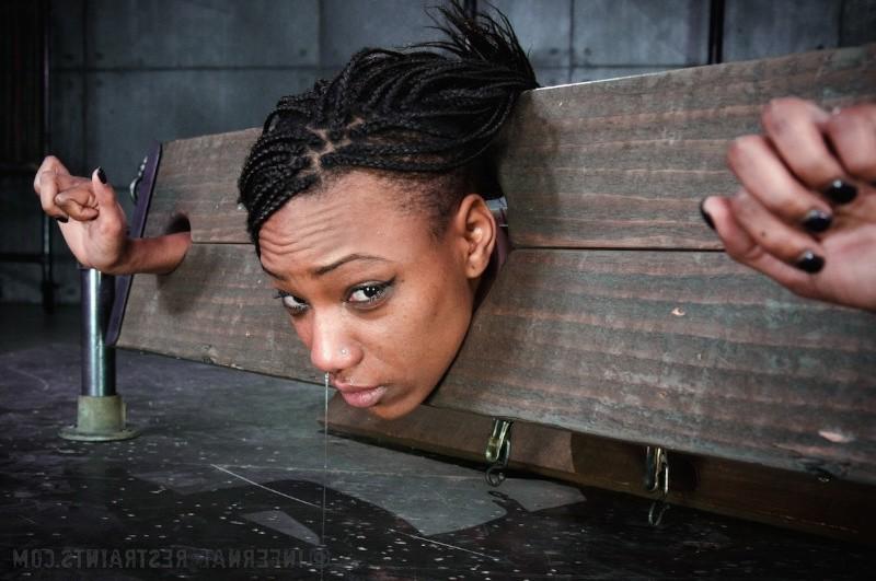 16P Nikki Darling ebony is bound in wooden stocks her feet spanked