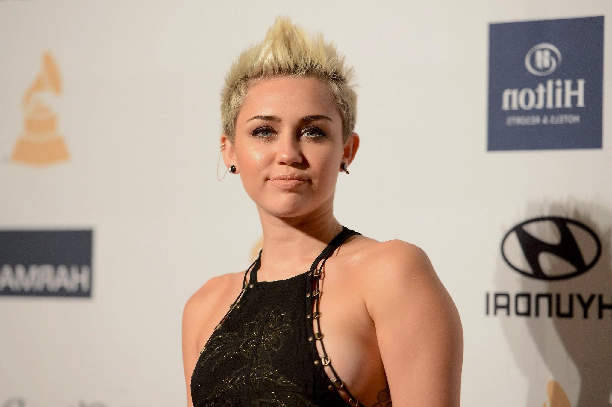 10P Miley Cyrus showing side boob in a black partially see-thru dress at Clive Davis