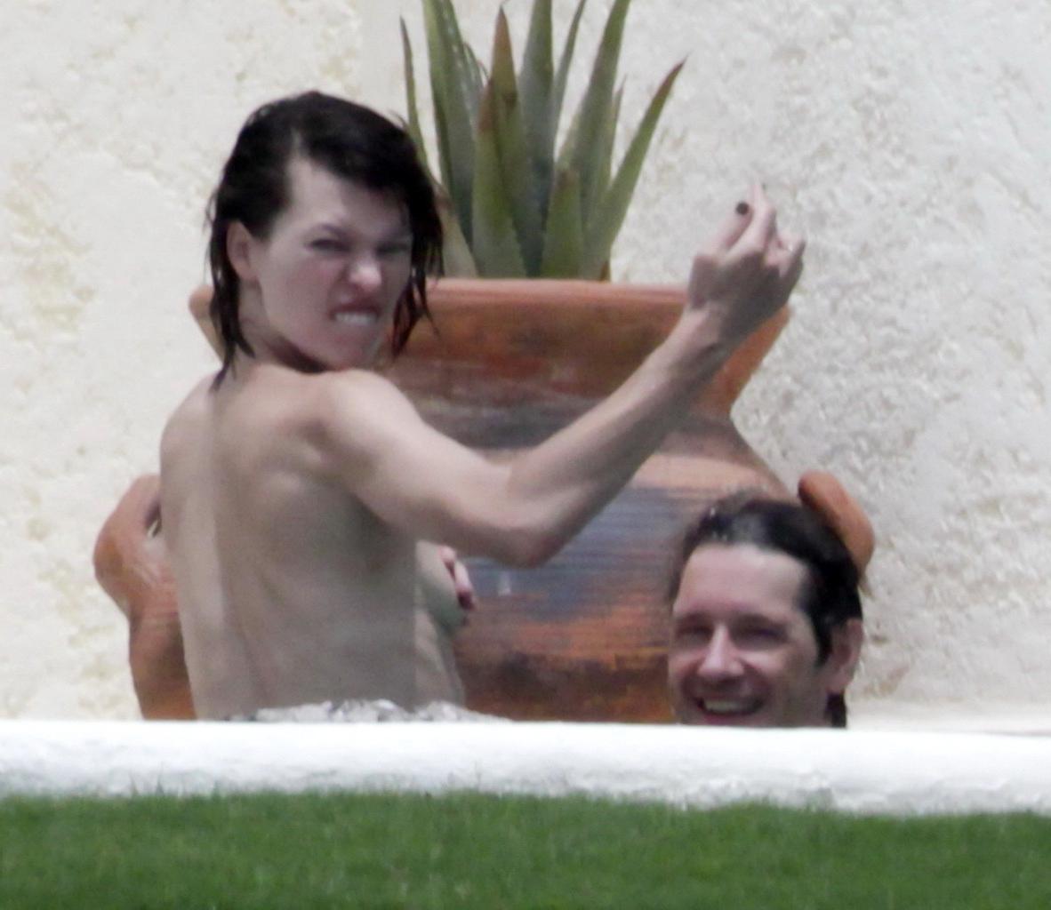 16P Milla Jovovich topless but hiding her boobs in Cabo San Lucas