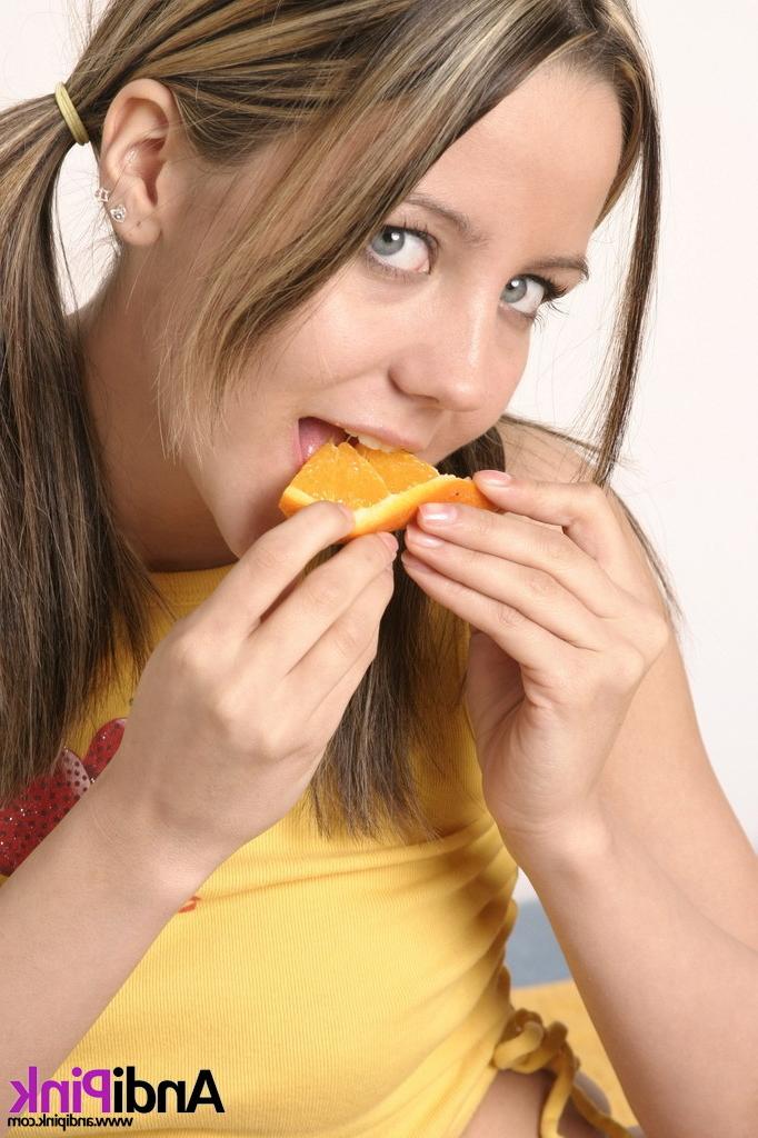 16P Cute teen girl with pigtails eating orange