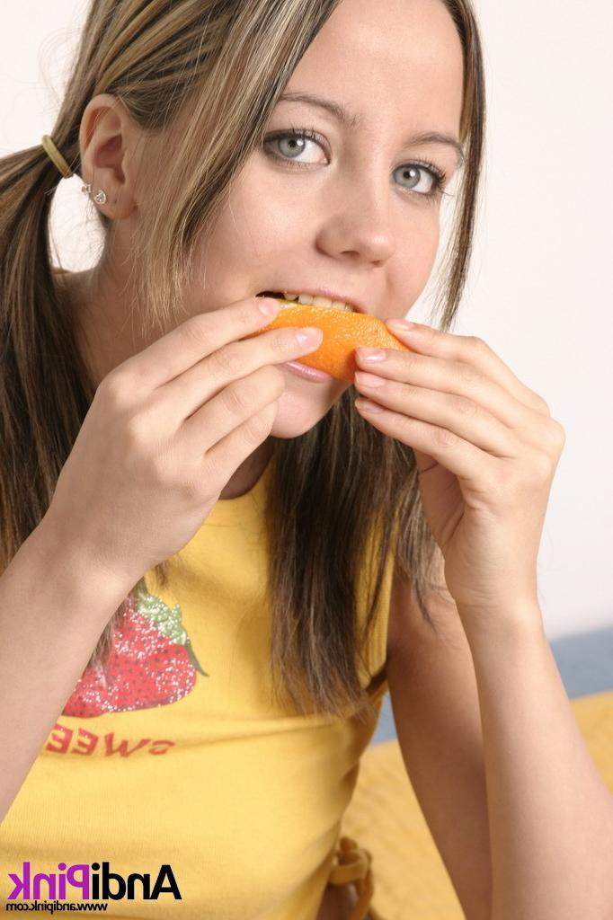 16P Cute teen girl with pigtails eating orange