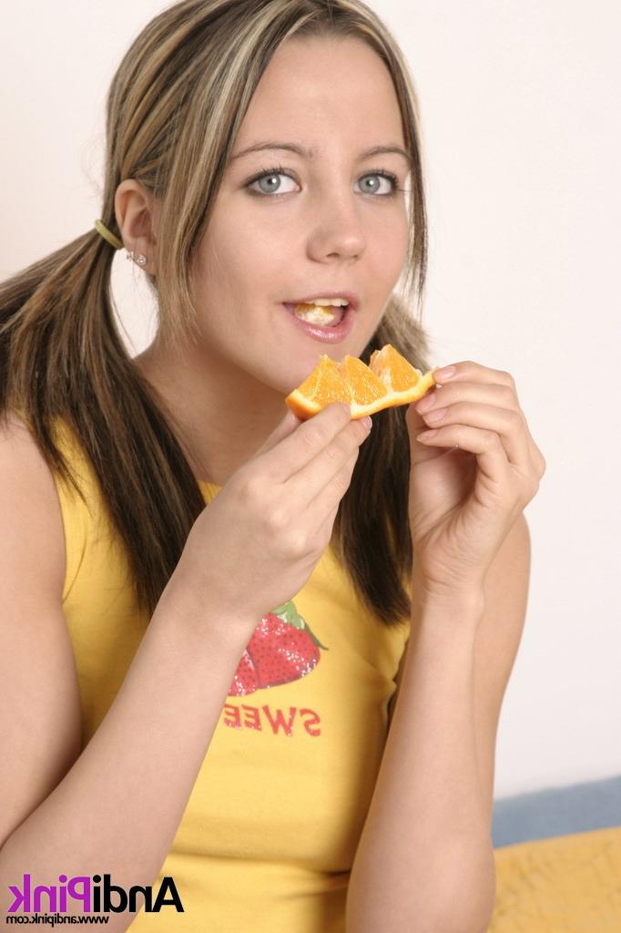 16P Cute teen girl with pigtails eating orange