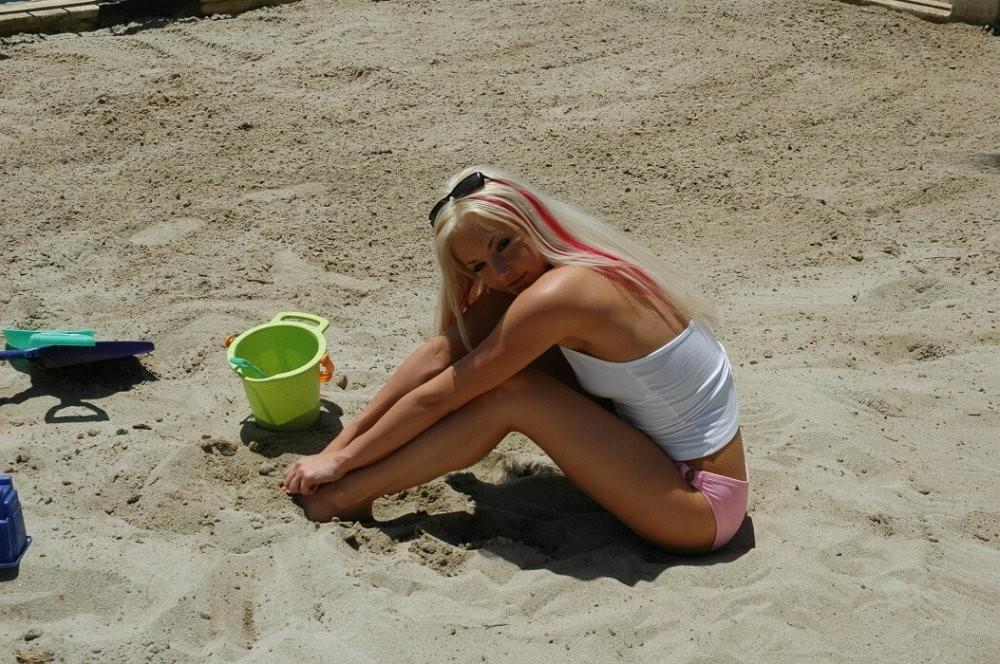 15P Cute bikini blonde girl showing off her titties on a sandy beach