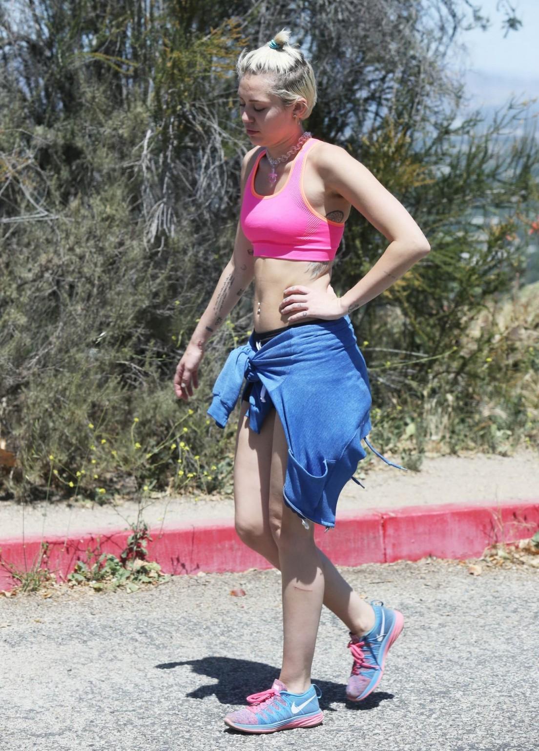 16P Miley Cyrus wearing pink sports bra and shorts out for a hike in LA