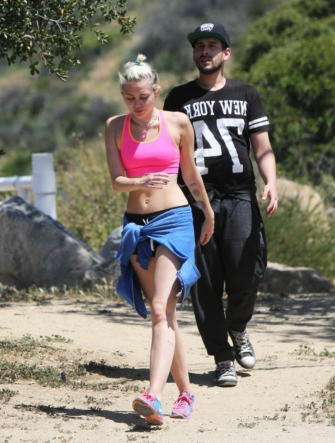 16P Miley Cyrus wearing pink sports bra and shorts out for a hike in LA